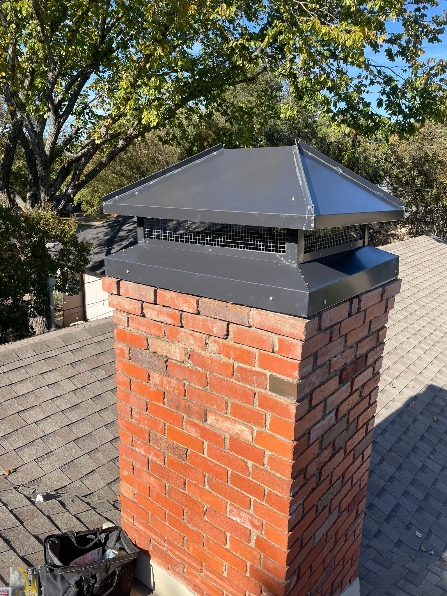 Custom hip-roof chimney cap installed on a red brick chase
